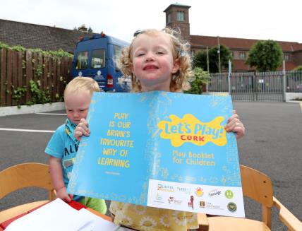 A child showing the logo of Let's Play Cork