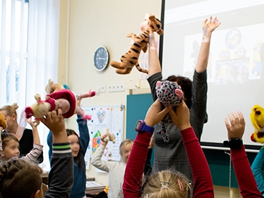 Children lifting their toys in the air during an active school activity at Sendvaris Progymnasium in Klaipeda